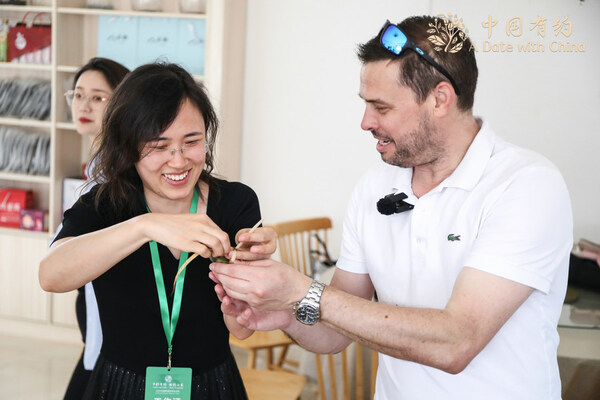 Nick Ive, a British editor with China Daily, is guided to make a zongzi in Weihai, East China’s Shandong province, on June 7, 2024. [Photo provided to chinadaily.com.cn]