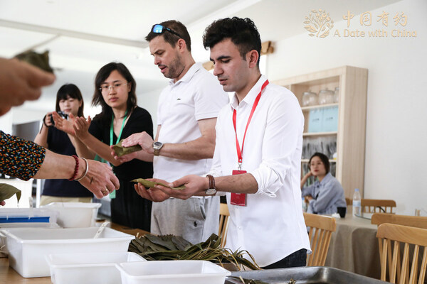 Members of the “A Date with China – Meet Shandong” international media tour, learn to make zongzi in Weihai, East China’s Shandong province, on June 7, 2024. [Photo provided to chinadaily.com.cn]