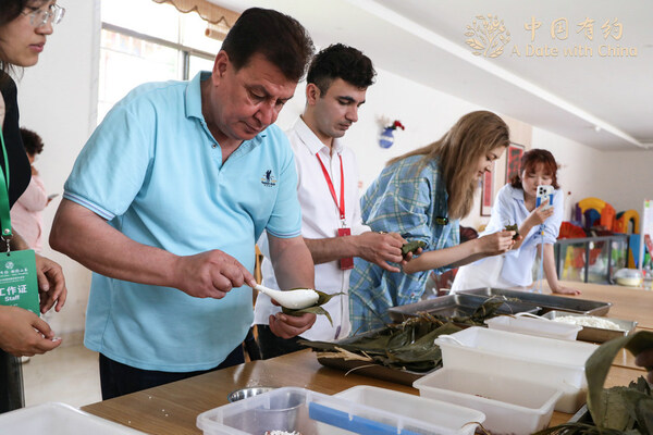 Members of the “A Date with China – Meet Shandong” international media tour, learn to make zongzi in Weihai, East China’s Shandong province, on June 7, 2024. [Photo provided to chinadaily.com.cn]